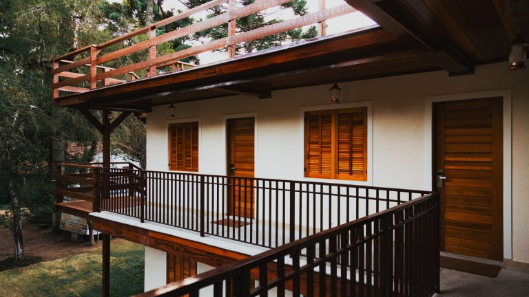 Serene wooden lodge featuring balconies, doors and windows surrounded by lush greenery