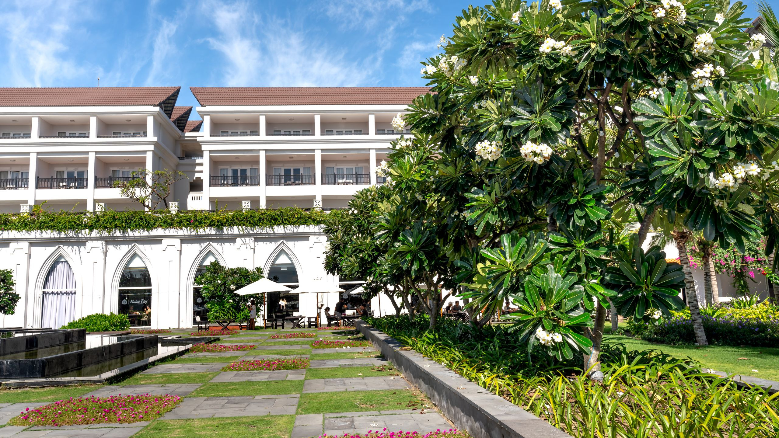Lush hotel garden with flowering trees and an elegant building facade