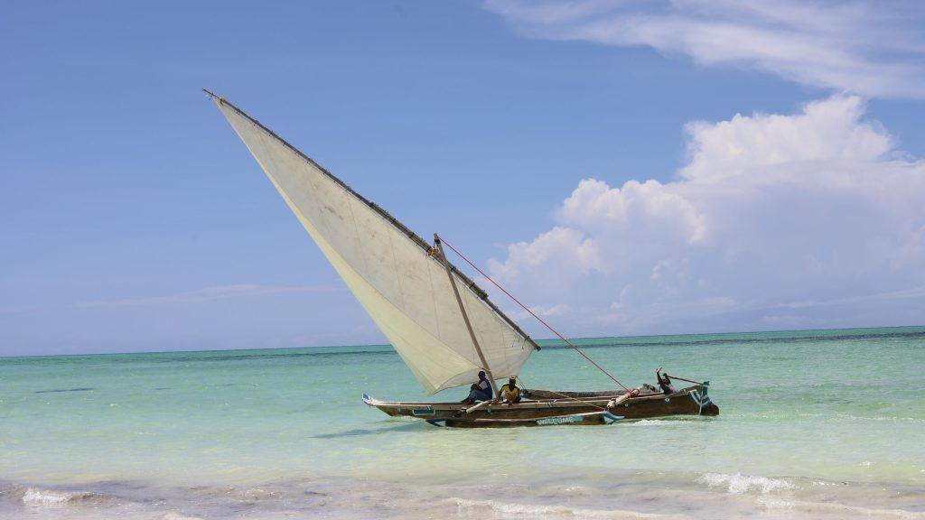 Traditional wooden dhow sailing near the Zanzibar shoreline under a clear blue sky