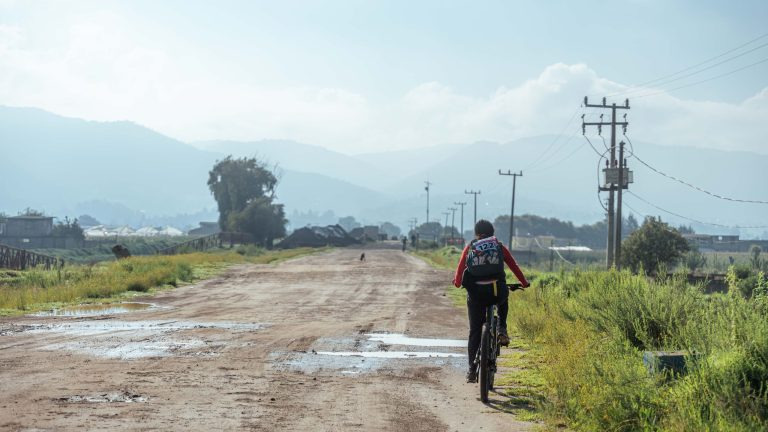 Cyclist riding along a scenic dirt road through the Kenyan highlands near Lake Naivasha
