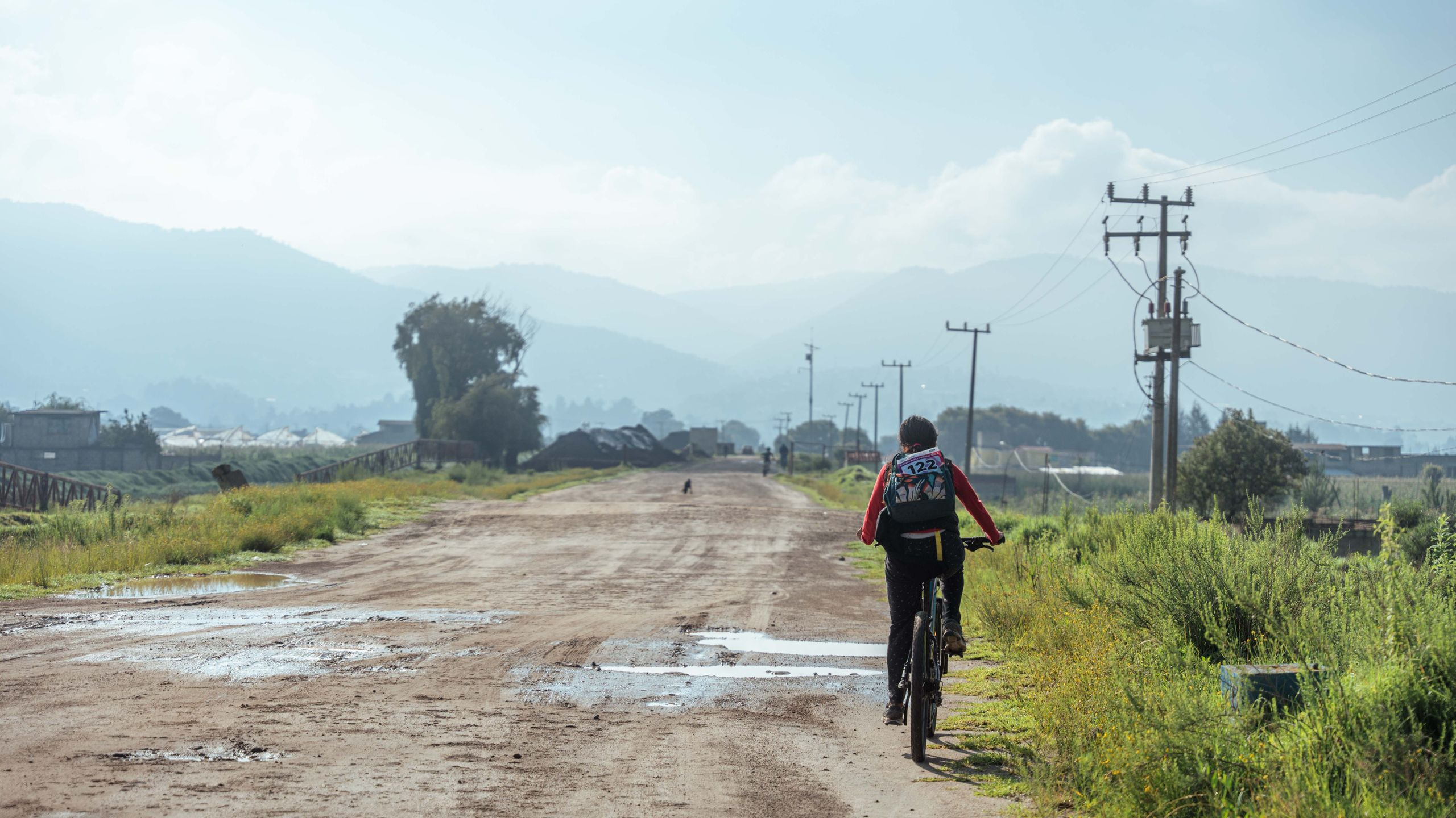 Cyclist riding along a scenic dirt road through the Kenyan highlands near Lake Naivasha