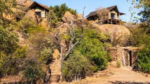 Rustic safari lodge buildings set among rocky, dry-country landscape