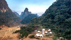 Aerial view of luxury safari tents set within a green valley landscape