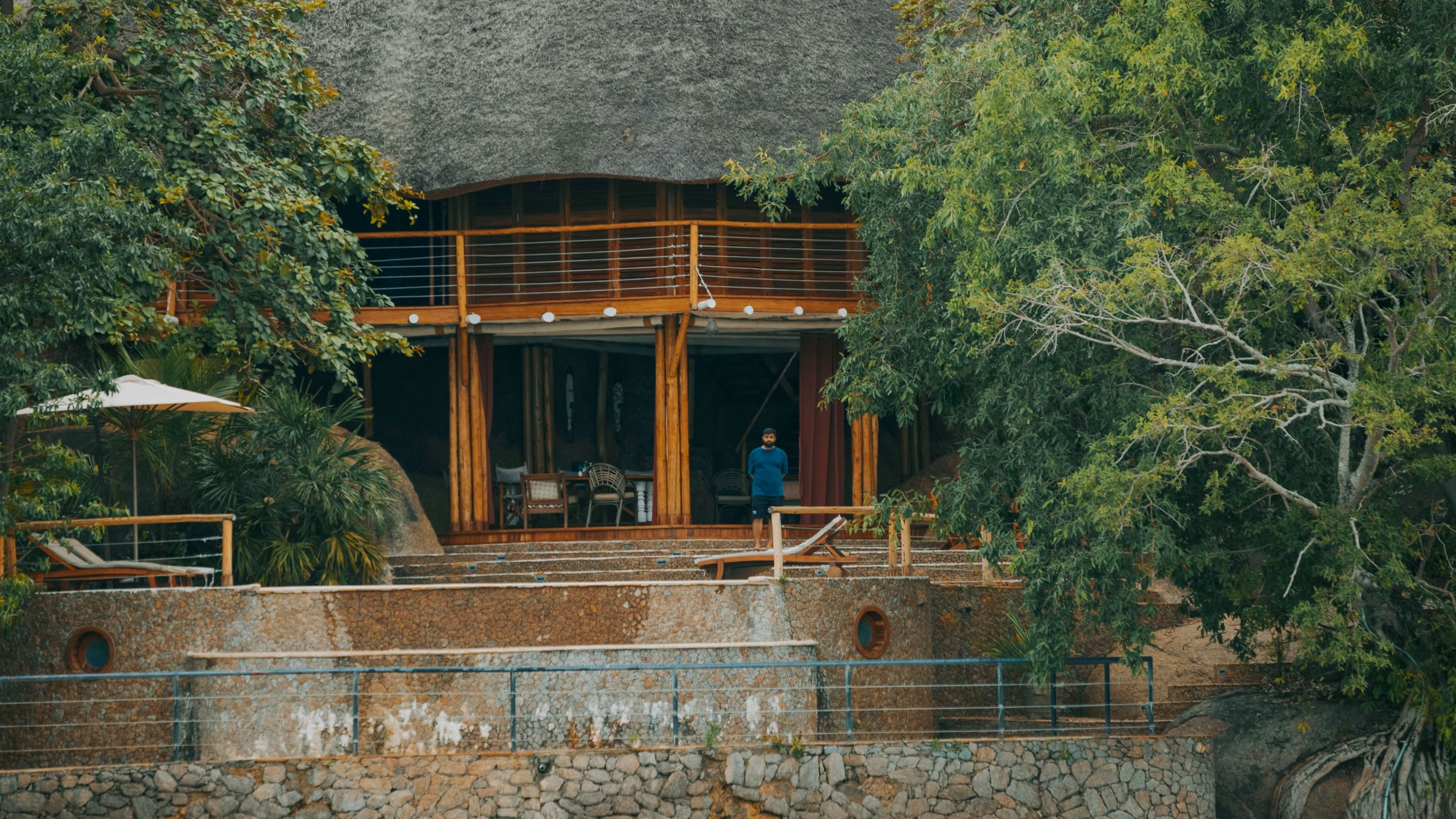Rustic lakeside lodge nestled among lush trees with a guest at the entrance
