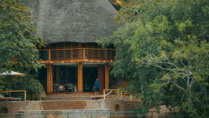 Simple thatched-roof lodge building nestled among lush green trees