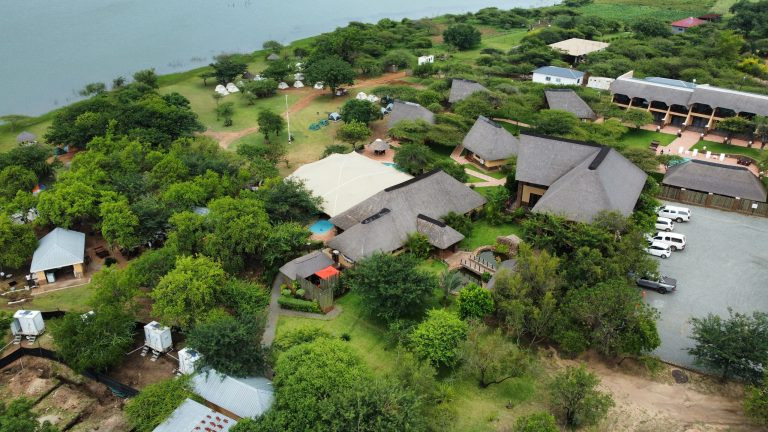 Aerial view of a picturesque lodge perched amid lush greenery, overlooking water