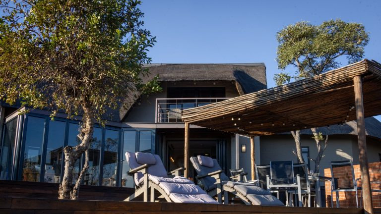 Elegant outdoor patio at a safari lodge with sun loungers and a natural wood pergola