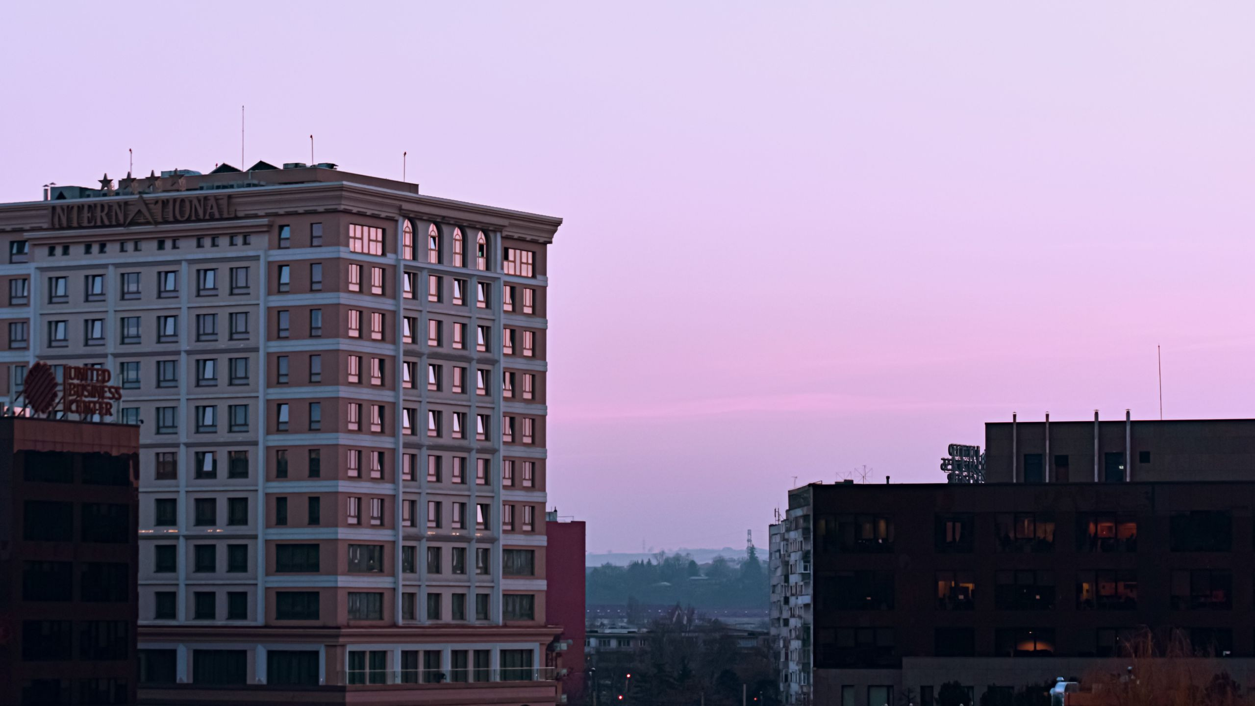 Modern four-star hotel complex exterior lit at colorful sunset