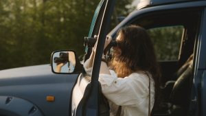 A traveler uses binoculars to scan the landscape from an open safari vehicle