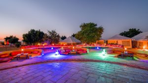 Elegant tented camp at dusk with vibrant outdoor seating